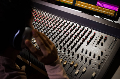 錄音室里坐著帶耳機(jī)的聲音制作人的剪裁鏡頭